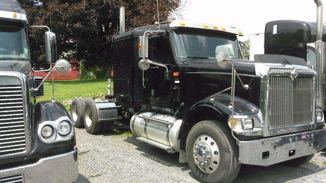 Black 2007 International 9900i conventional sleeper truck showing chrome grille, large front bumper, dual round headlights, and side fuel tanks.