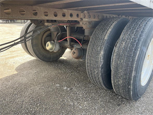 Trailer axle area showing dual rear tires, suspension, and brake assemblies under a Wabash dry van.