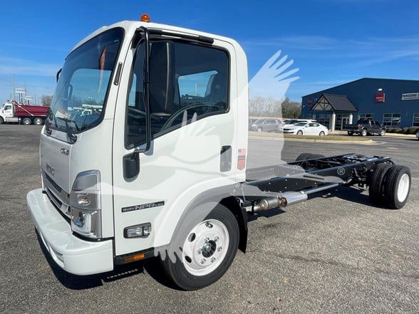 Isuzu NPR HD cab chassis truck with white cab, front-left view, chassis exposed rear without bed. Clear windshield, side mirror, and orange cab beacon.