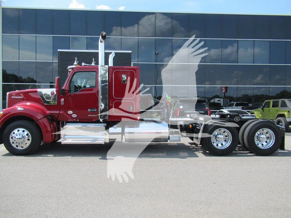 Kenworth W990 conventional sleeper truck in red with chrome steps and dual rear axles, parked in front of a glass building.