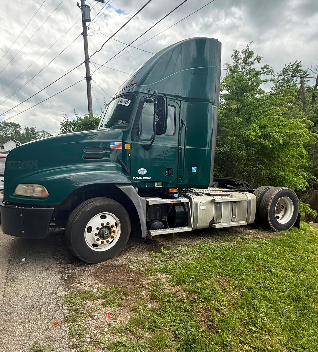 Green 2016 Mack CXU612 conventional daycab semi-truck side view showing cab, fuel tanks, and rear tractor area with wheels.