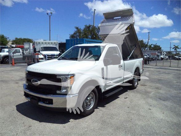 2017 Ford F250 dump truck with dump bed raised in a lot. Front grille, headlights, and side mirrors visible.