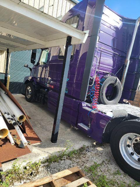Purple 2018 Volvo VNL 780 truck with sleeper cab parked beside building; visible tires, exhaust, and chrome components.