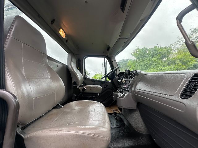 Freightliner 114SD truck cab interior/cockpit showing driver and passenger seats, dashboard, and steering wheel.