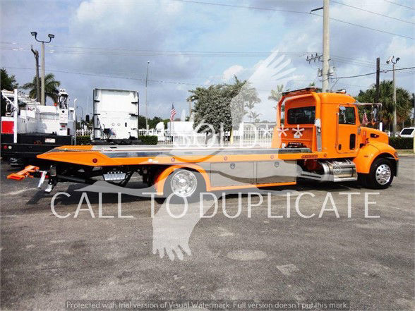 2022 Peterbilt 337 tow truck in orange with long flatbed, side view showing cab and hydraulic equipment.