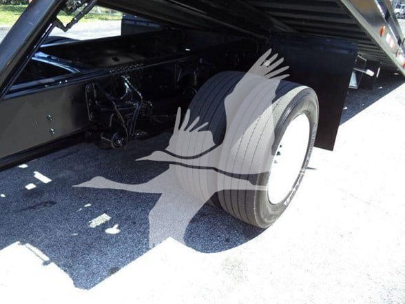 Rear wheel and undercarriage of a 2015 Ford F650 XLT tow truck with dual wheels and black chassis. Watermark of a bird logo overlays the image.