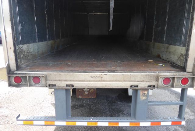 Open Great Dane trailer cargo area showing empty interior, rear doors up, rear bumper with taillights and reflective strip.