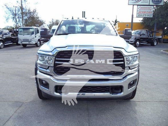 Front view of a white 2024 Ram 5500 SLT truck with large grille and RAM logo; dealership lot in background.