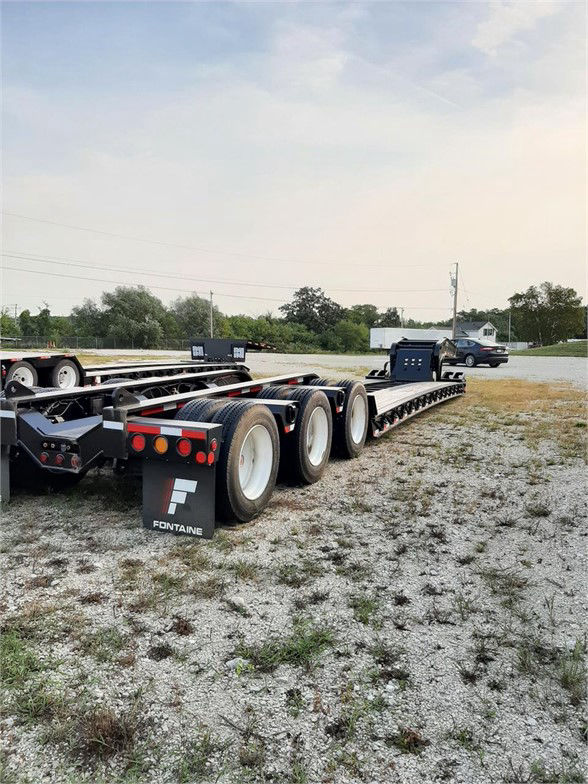 Fontaine 55 ton steel lowboy trailer with 26 ft deck, multiple axles, black and gray frame, rear tires, Fontaine logo on mudflap.