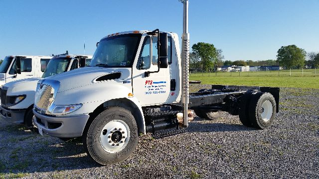 International 4300 SBA 4x2 cab and chassis truck in a lot, white, with dual rear axles and vertical exhaust stack.