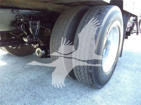 Rear dual tractor tires and undercarriage of a reefer truck showing suspension components and wheel.