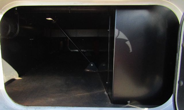 Truck cab storage area showing interior side panels and a vertical partition, with a dark, glossy surface on the right and a floor space on the left.