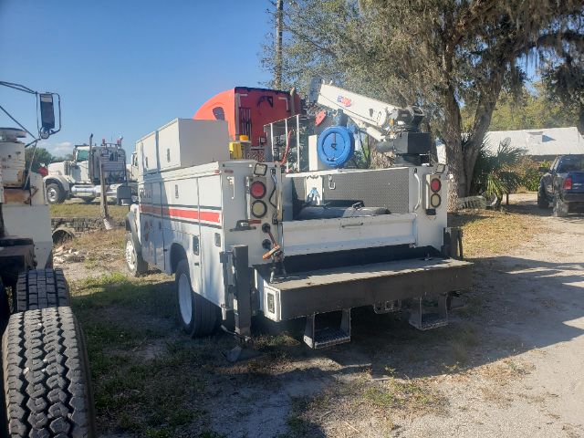 Utility truck with crane rear equipment and toolbox mounted on a white service body, viewed from the rear-right side.
