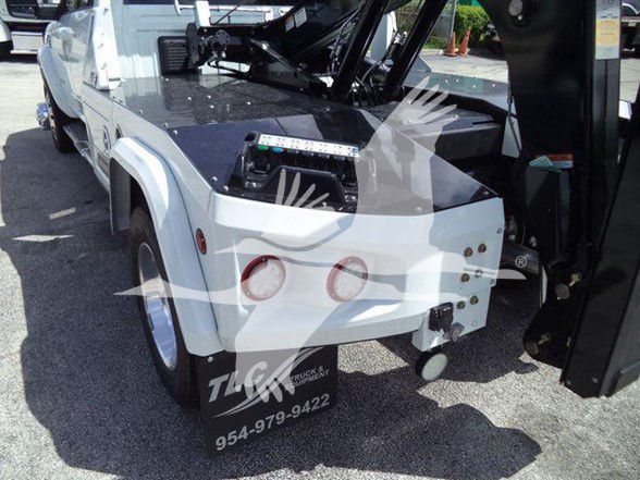 Ram 5500 Laramie tow truck rear view showing white body, black equipment, and hydraulics in the pickup bed area.