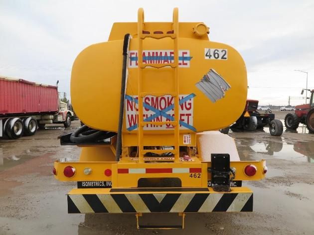 Rear view of a yellow fuel tanker truck with hazard stripes, decals, and the number 462. Tank is mounted on a chassis with hoses and access ladder visible.