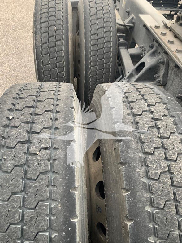 Truck dual rear tires showing tread and wheel rims, with other tires in background.
