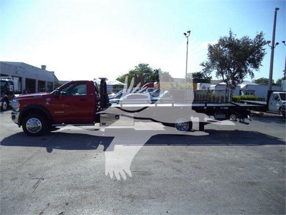 Ram 5500 chassis cab truck with a flatbed trailer in a dealership lot and watermarked image.