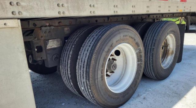 Trailer tires visible under a utility trailer with dual rear axles. Rim and tire details are visible; no clear branding legible.