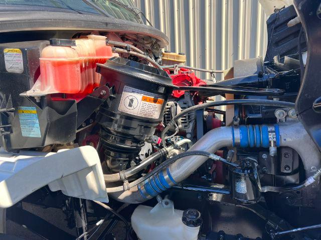 Freightliner M2 106 dump truck engine bay showing coolant reservoir, air filter housing, and various hoses with blue silicone couplers.