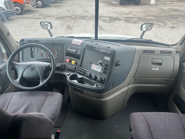 Freightliner Cascadia 125 truck interior, dashboard and steering wheel with gauge cluster, controls, and center console visible.