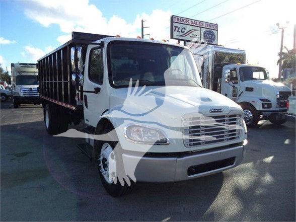 2012 Freightliner Business Class M2 106 dump truck front-left view with white cab and black dump bed at a dealership lot.