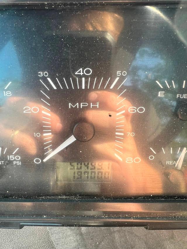 Dashboard gauge cluster showing a speedometer with MPH up to 60-80, tach/pressure gauges, and an odometer Digital display. Reflections visible.