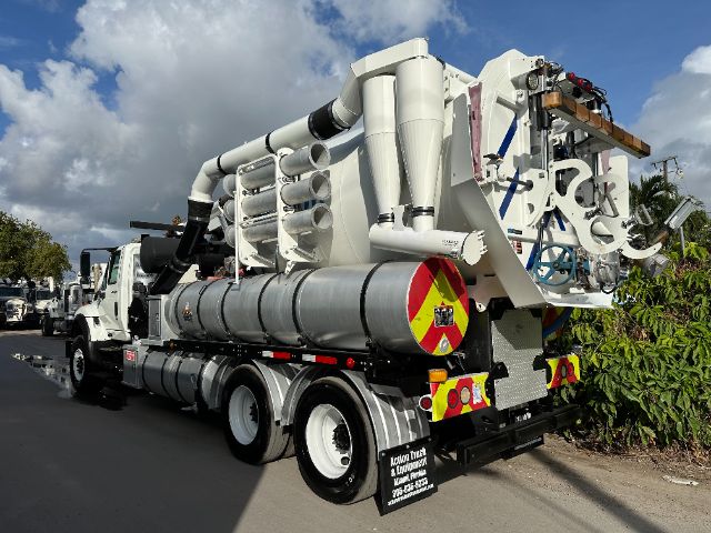 Vacuum truck rear view showing large white piping and storage tank on a multi-axle International 7500 vacuum unit.