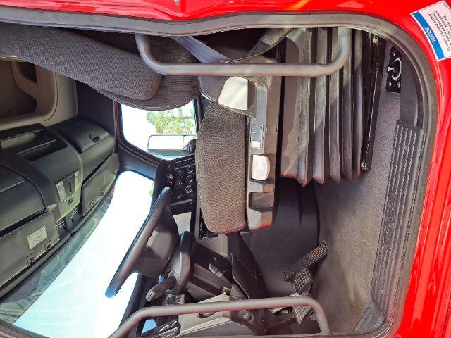 Freightliner Cascadia truck interior showing driver's seat, pedals, and dashboard. Visible components include steering wheel, center console, and entry step.