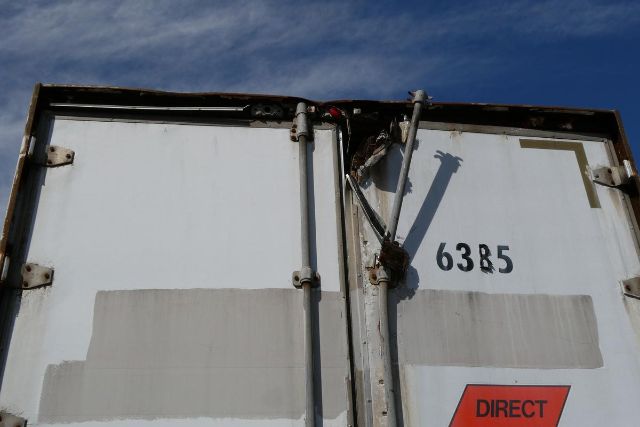 Rear of a trailer door with vertical latch bars and the number 6385 visible; Direct label in lower right corner.