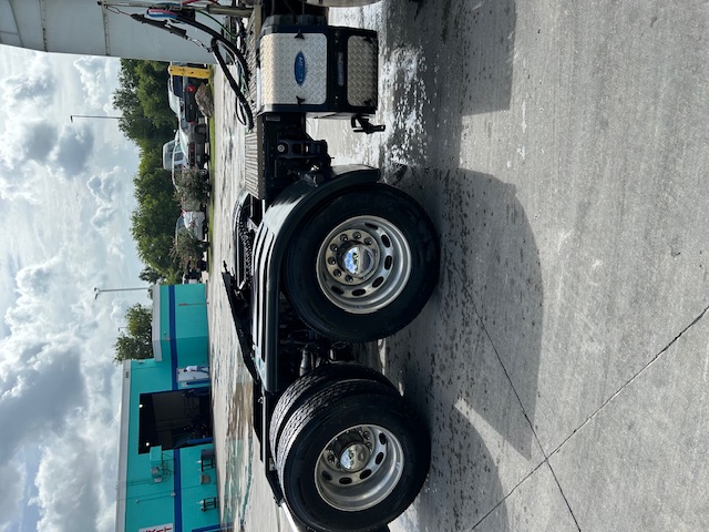 Peterbilt 579 tractor rear axle area showing dual rear wheels, fuel tank, and side fairing with chrome accents.