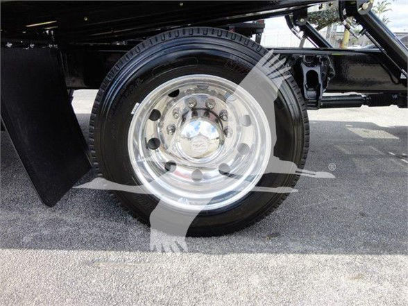 Wheel and tire of a Peterbilt truck with chrome hubcap, undercarriage visible; part of rear wheel area.