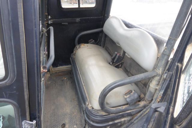 Club Car Carryall 1700 interior showing a single gray bench seat and a large cylindrical fuel tank or ballast in the cargo area with metal rails and guards.