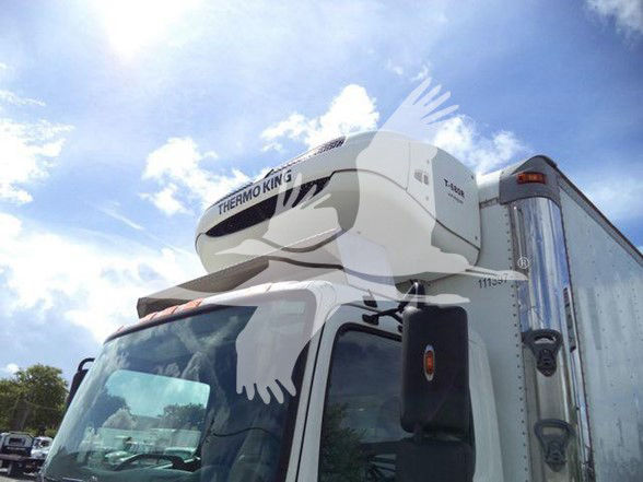 Truck cab with Thermo King reefer unit on top showing side mirror and refrigerated trailer.