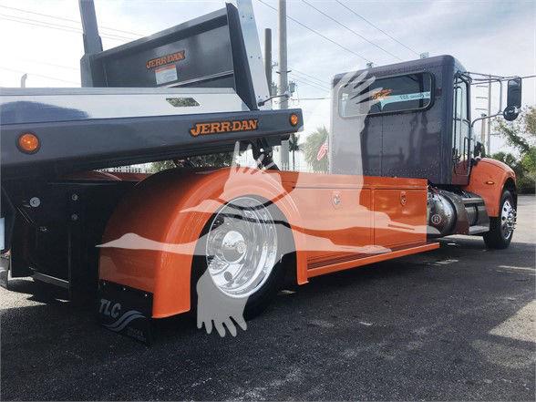 Truck wheel area with orange and black Peterbilt tow truck body, Jerr-Dan branding on the towing equipment, visible wheel, orange fenders, and cab in background.