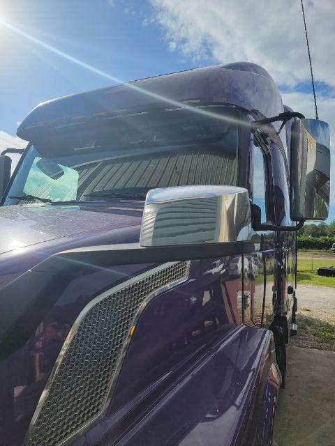 Volvo VNL 780 truck cab side view showing driver mirror and hood with chrome accents.