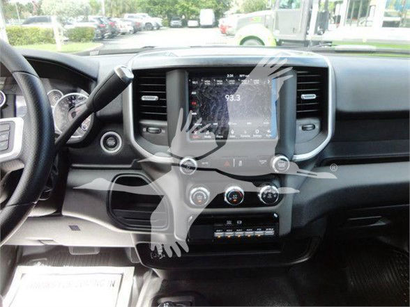 Ram truck interior showing large touchscreen infotainment display, climate controls, and steering wheel. Center console with knobs and vents visible.