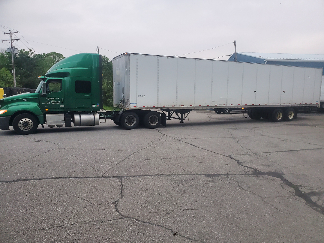Green 2019 International LT truck with a long silver trailer in a parking lot.