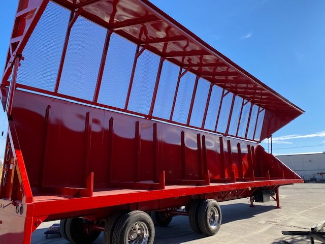 Crush car carrier trailer in red with tall side panels and mesh top rails, 48-foot length, dual rear axles visible.