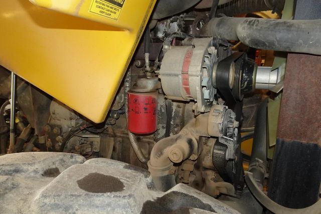 VM106D engine bay showing alternator and red oil filter among piping and belts.