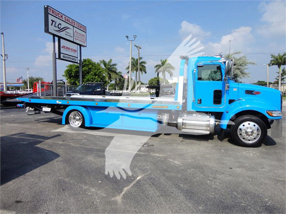 2022 Peterbilt 337 tow truck side view showing blue cab and flatbed bed with chrome fuel tanks and wheels.