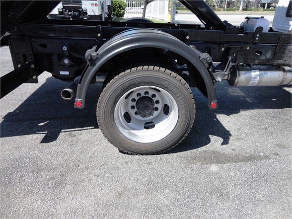 Ram 5500 HD chassis with spare wheel and hooklift components visible, rear wheel and fuel tank on passenger side.