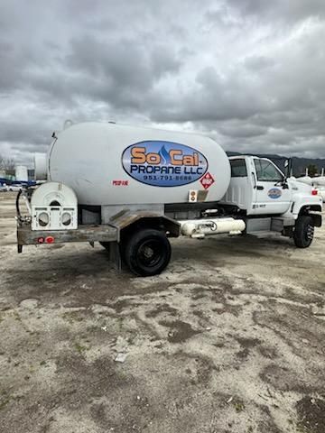 Vehicle side view shows a white tanker truck with SoCal Propane logo, cylindrical tank on a white cab, rear dual wheels, and a visible hose connection.