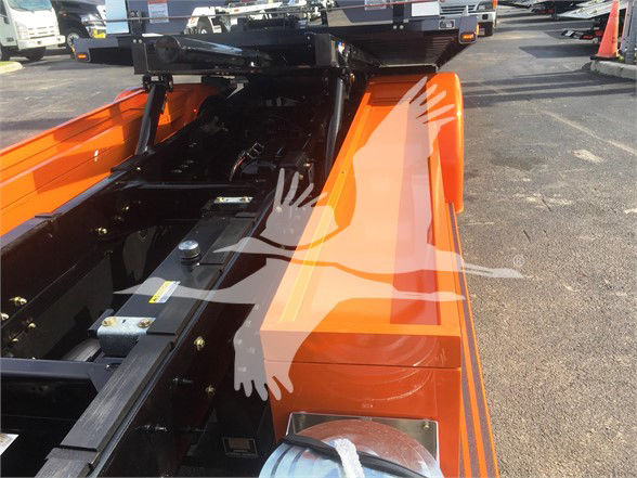 Orange Peterbilt 337 chassis frame with equipment hitch and undercarriage view, showing metal rails and hydraulic components.