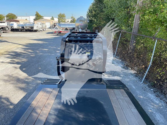 Trailercam shows a 2024 XL Specialized Mini Deck trailer with wood and steel deck; front area shows a black toolbox and ladder rack; visible branding on a sticker reads 'HOT' or similar; background includes other trailers and yard.