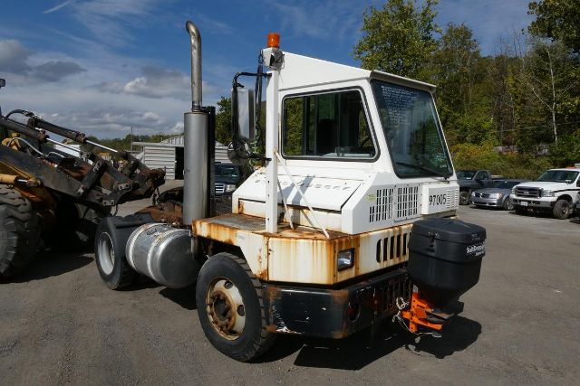 Ottawa YT30 yard truck showing cab with exhaust stack, rust on lower body, spare tire mounted, and fuel/diesel tank visible.