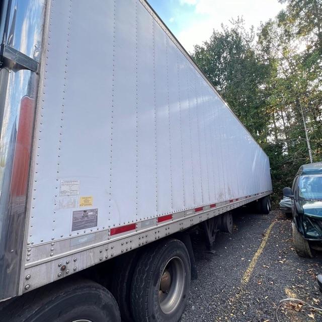 Trailer side view showing a white Wabash Arctic Lite refrigerated semi-trailer with riveted aluminum panels and tandem axles.