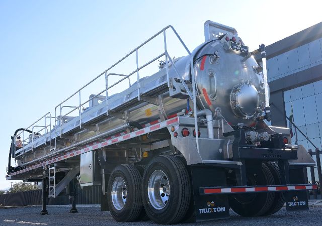 Truxton 150BBL aluminum non-code vacuum trailer with cylindrical tank, rear access hatch, and dual rear axles. visible ladders rails and Truxton branding on mud flaps.