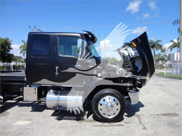 Truck cab with hood open showing side view of International MV truck, chrome fuel tank, black cab, wheel, and engine area visible.