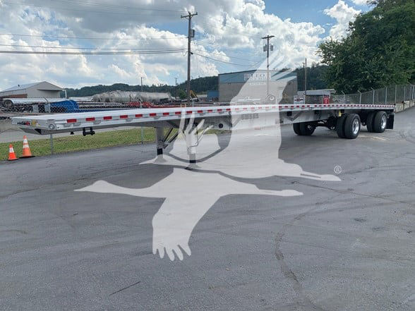 Flatbed trailer with sliding rear axle, long aluminum deck, and dual rear axles visible; watermark covering image.