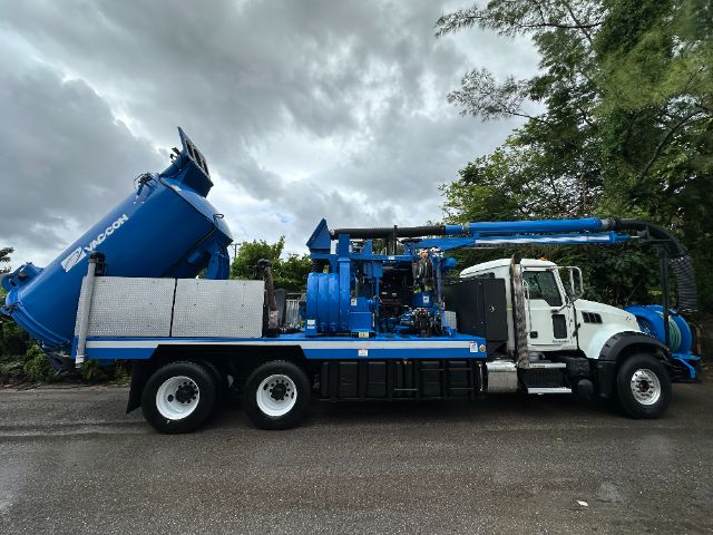 2017 Mack GU713 vacuum truck with blue body, white cab, large blue vacuum tank, and attached hoses.